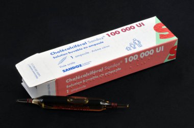 Box of cholecalciferol and a drinkable ampoule close-up on a black background 