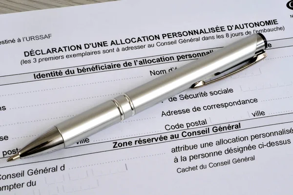 French declaration form for a personalized autonomy allowance with a pen lying on it 