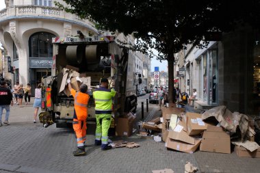 Vannes, France, August 17, 2022 : Garbage collectors putting boxes in a garbage truck in the city of Vannes in Brittany