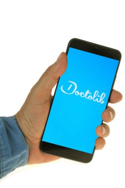 Doctolib application on a smartphone held in hand close-up on a white background 