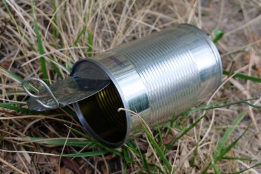 Open and empty tin can in the grass close-up