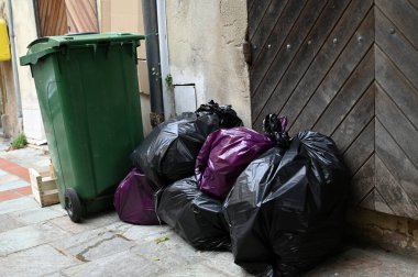 Çöp tenekesi ve çöp torbaları bir sokakta 