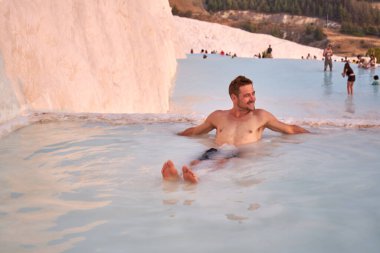 Pamukkale Doğal Parkı 'nda Türkiye' de beyaz travertin arasında yüzen mutlu bir gezgin. Genç adam Pamukkale doğal parkında güzel manzaralı bir havuzda dinleniyor..                      