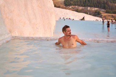 Pamukkale Doğal Parkı 'nda Türkiye' de beyaz travertin arasında yüzen yakışıklı gezgin. Genç adam Pamukkale doğal parkında güzel manzaralı havuzda dinleniyor..                                    