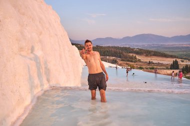 Pamukkale Doğal Parkı 'nda Türkiye' de beyaz travertin arasında yüzen mutlu bir gezgin. Genç adam Pamukkale doğal parkında güzel manzaralı bir havuzda dinleniyor..                      