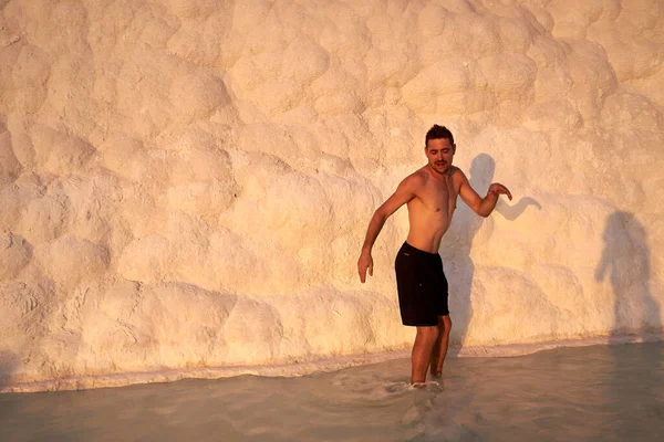 Pamukkale Doğal Parkı 'nda Türkiye' de beyaz travertin arasında yüzen mutlu bir gezgin. Genç adam Pamukkale doğal parkında güzel manzaralı bir havuzda dinleniyor..                      