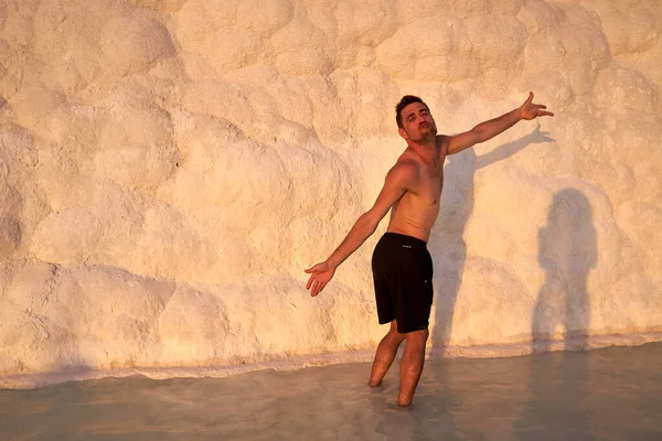 Pamukkale Doğal Parkı 'nda Türkiye' de beyaz travertin arasında yüzen mutlu bir gezgin. Genç adam Pamukkale doğal parkında güzel manzaralı bir havuzda dinleniyor..                      