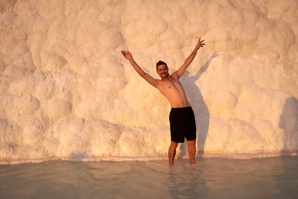 Pamukkale Doğal Parkı 'nda Türkiye' de beyaz travertin arasında yüzen mutlu bir gezgin. Genç adam Pamukkale doğal parkında güzel manzaralı bir havuzda dinleniyor..                      