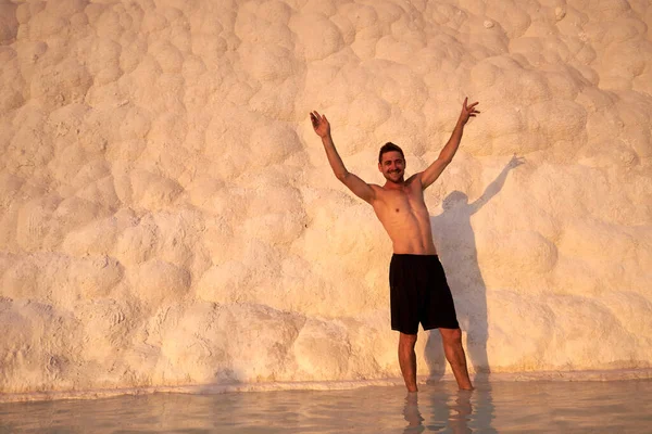 Pamukkale Doğal Parkı 'nda Türkiye' de beyaz travertin arasında yüzen mutlu bir gezgin. Genç adam Pamukkale doğal parkında güzel manzaralı bir havuzda dinleniyor..                      