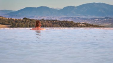 Türkiye 'de Pamukkale traverteni, manzaranın tadını çıkaran bir adam. Pamukkale Doğal Parkı 'nda yüzen ve güzel bir gün batımına bakan bir gezgin. Pamukkale' de dinlenen genç bir adam.              