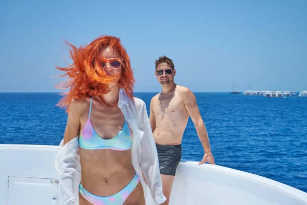 Couple in love standing on luxury yacht  while sailing in the Red sea. Handsome man and beautiful red hair woman having romantic travel. Romantic couple on yacht on honeymoon