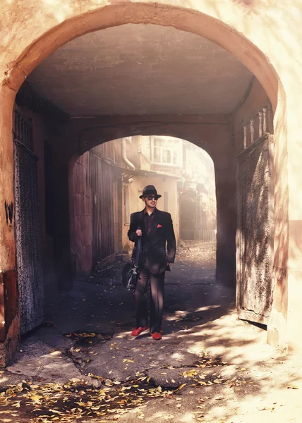 Elegante hombre con traje y sombrero atraviesa el arco —  Fotos de Stock