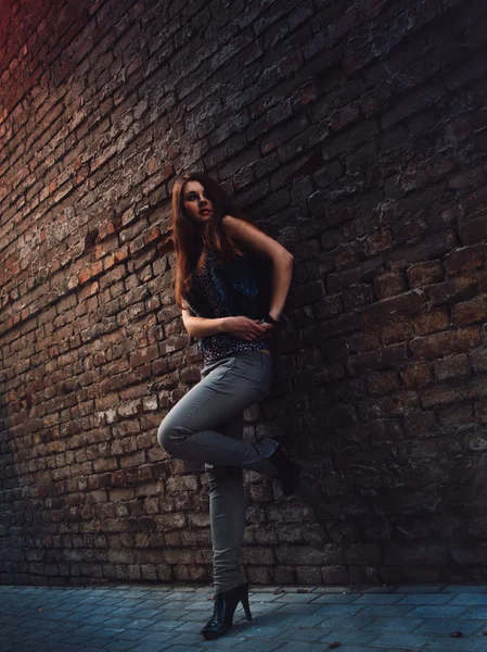 Jolie fille avec des cheveux roux debout près du mur de briques — Photo