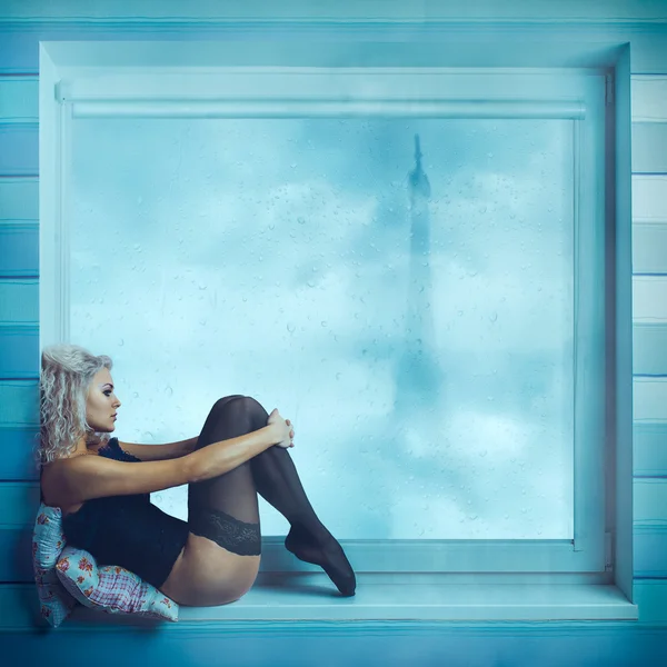 Sexy lockige Blondine sitzt im Korsett am Fenster — Stockfoto