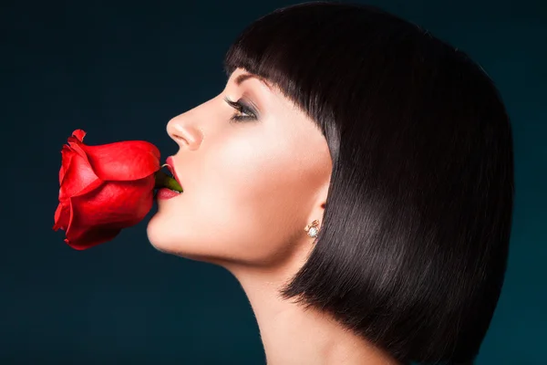 Retrato de media cara de mujer bonita con rosa roja en la boca —  Fotos de Stock