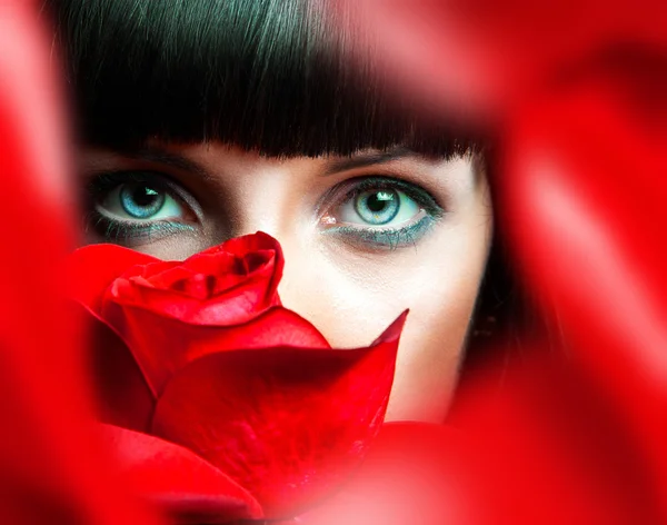 Mooie brunette achter rode roos in studio — Stockfoto