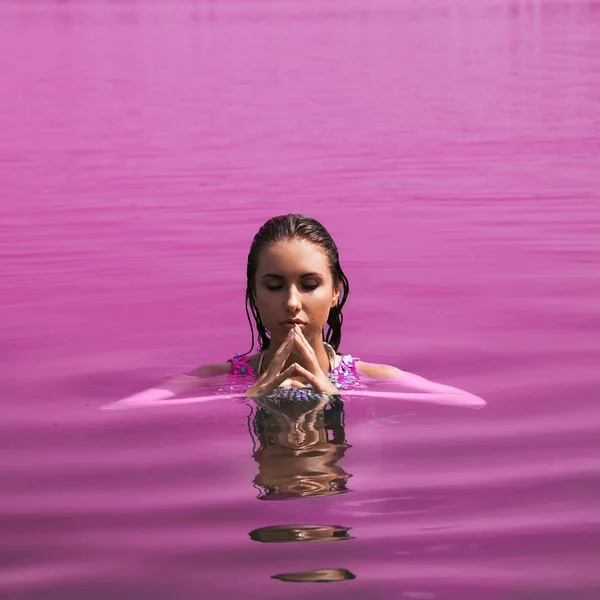 Mujer adulta con los ojos cerrados en agua rosa — Foto de Stock