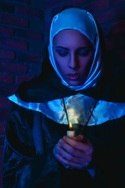 Cold tones portrait of female monk with candle in hands — Stock Photo, Image