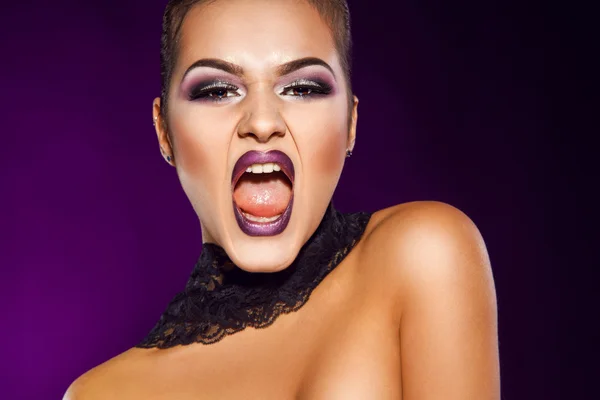 Wanita muda cantik berteriak di studio dengan latar belakang ungu — Stok Foto