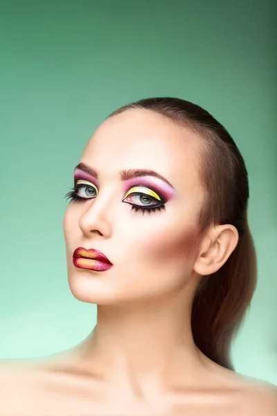 Mujer atractiva con maquillaje multicolor sobre fondo verde — Foto de Stock