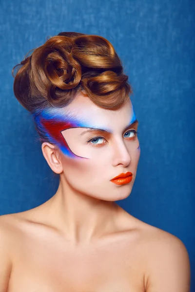 Kaukasische vrouw met creatieve make-up en haarstijl op blauwe rug — Stockfoto