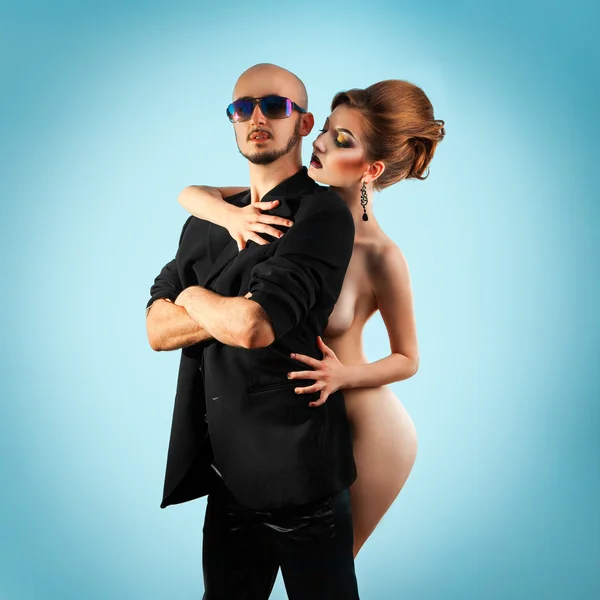 Serious strong man with hot naked woman in studio — Stock Photo, Image