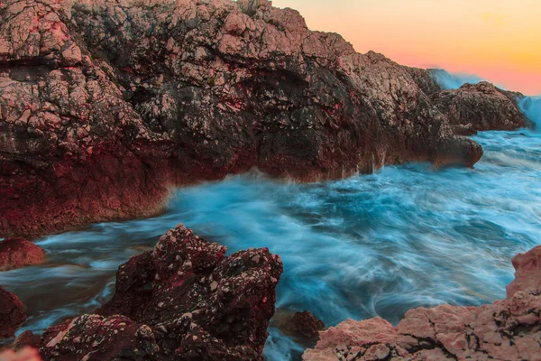 Хвилі океану розбиваються на скелях під час заходу сонця — стокове фото