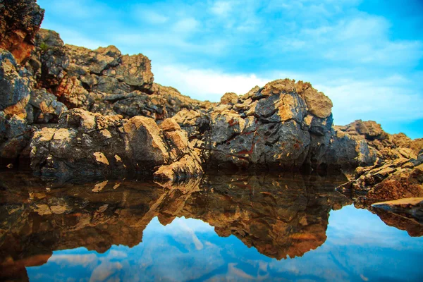 Rochas e seu reflexo no mar durante o dia — Fotografia de Stock
