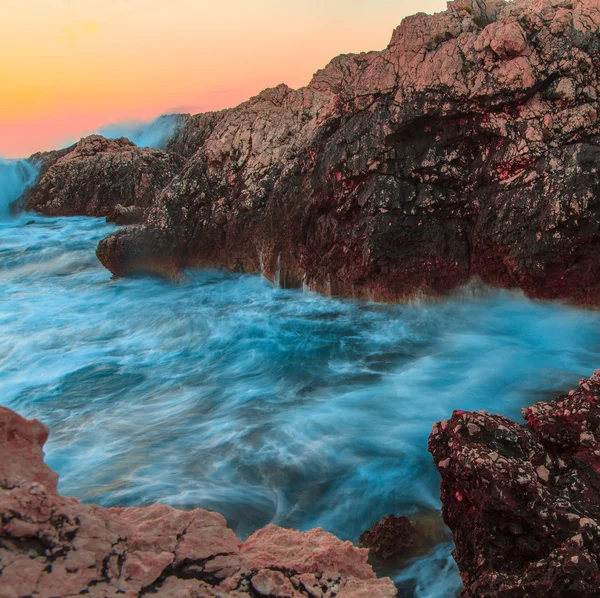 Хвилі океану розбиваються на скелях під час заходу сонця — стокове фото