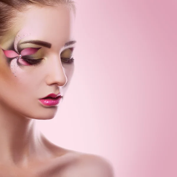 Jonge volwassen vrouw met gesloten ogen en creatieve make-up op roze b — Stockfoto