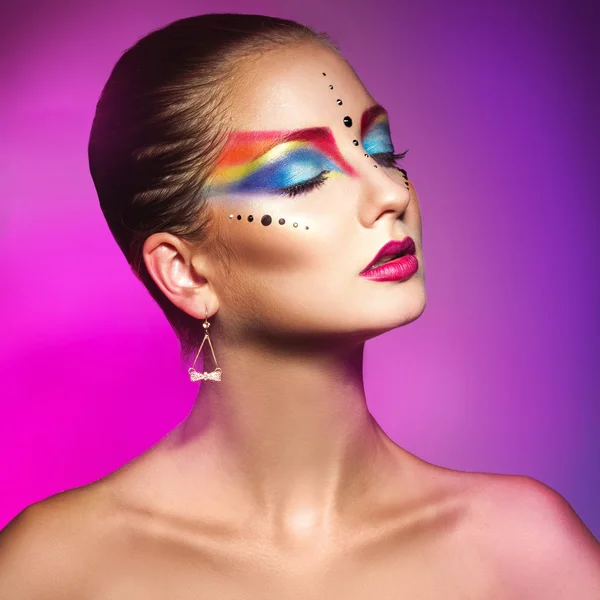 Encantadora mujer con maquillaje colorido sobre fondo púrpura — Foto de Stock