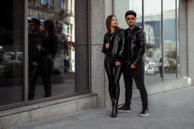 Şehirde poz veren deri elbiseli güzel bir çiftin göz alıcı portresi.