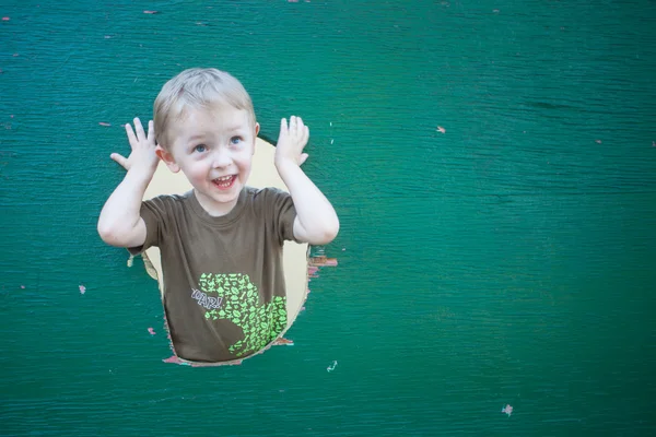 Çocuk yeşil duvardan göz atar.