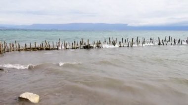 Dalgalar kıyıya sert vurur ve antik iskelenin kalıntılarını dağıtır. Ufuk uzaklardan görülebilir..