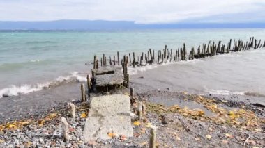 Dalgalar kıyıya sert vurur ve antik iskelenin kalıntılarını dağıtır. Ufuk uzaklardan görülebilir..