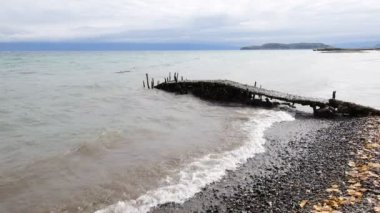 Dalgalar kıyıya sert vurur ve antik iskelenin kalıntılarını dağıtır. Ufuk uzaklardan görülebilir..
