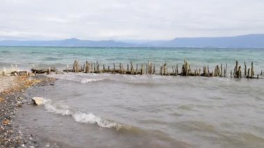 Dalgalar kıyıya sert vurur ve antik iskelenin kalıntılarını dağıtır. Ufuk uzaklardan görülebilir..