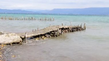 Dalgalar kıyıya sert vurur ve antik iskelenin kalıntılarını dağıtır. Ufuk uzaklardan görülebilir..