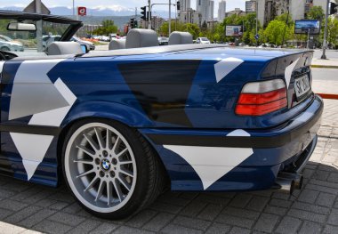 Spor araba BMW 3 e36 Cabriolet spor jantlı ve caddeye park edilmiş çıkartmalarla kaplı..