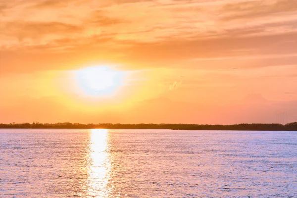 Puesta de sol en el terraplén del río Amur en Jabárovsk. Puesta de sol sobre el horizonte. Hojas de árboles de otoño en el fondo. —  Fotos de Stock