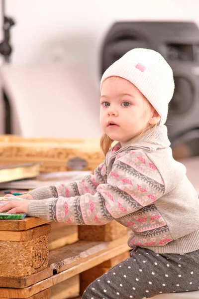 작은 소녀는 나무 팔레트로 만든 테이블에 펠트 펜으로 그림을 그립니다.. — 스톡 사진