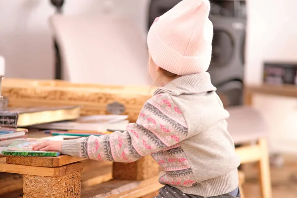 Küçük bir kız ahşap paletlerden yapılmış bir masaya keçeli kalemlerle resim çiziyor.. — Stok fotoğraf