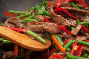 Cooking beef, capsicum and bean stirfry in wok clipart