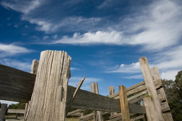 Vecchio recinto in legno con cielo blu e nuvole — Foto Stock