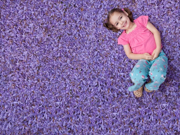 Meisje liggend op paarse bloemen — Stockfoto