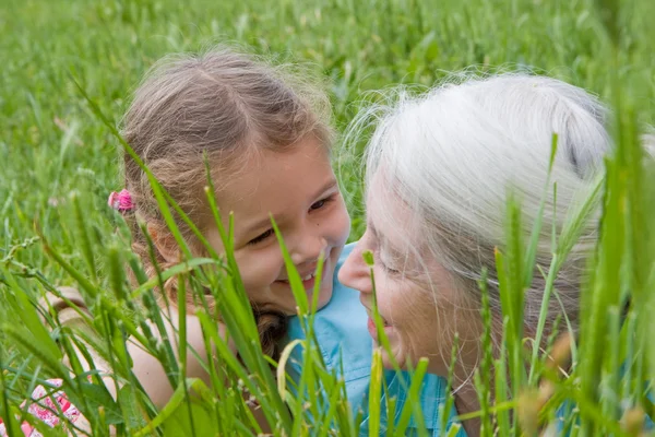Menina rindo com a avó na grama longa — Fotografia de Stock