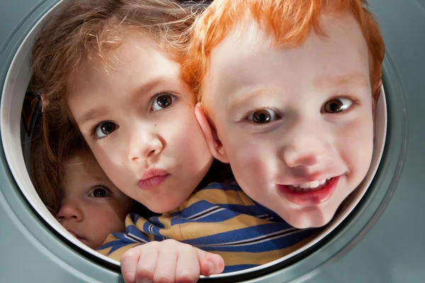 Happy kids looking through window porthole — Stock Photo, Image