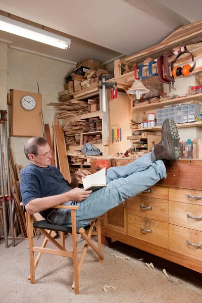 Muž odpočívat s nohama nahoře v dílně — Stock fotografie