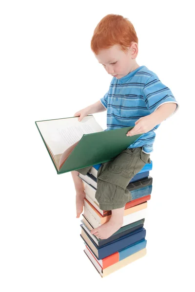 Junge liest auf Bücherstapel — Stockfoto