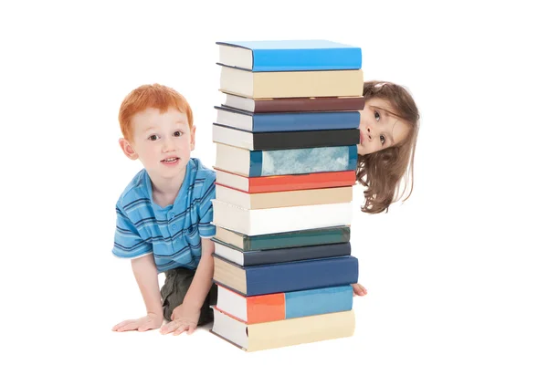 Kids hiding behind stack of books — Stock Photo, Image